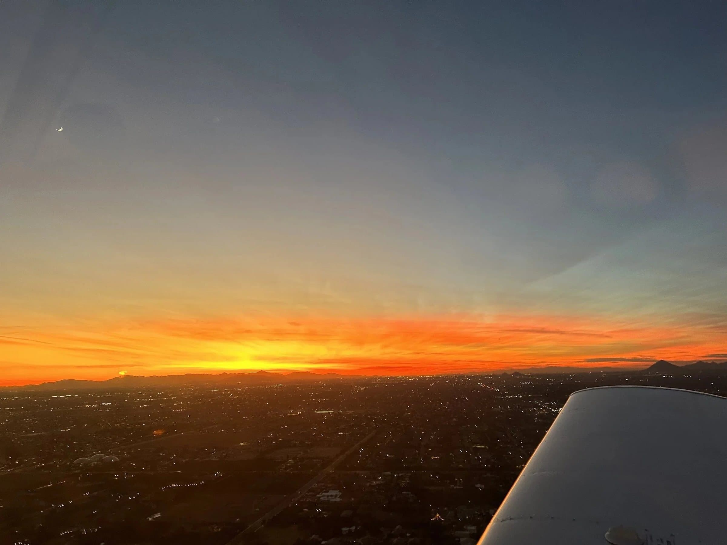 Sunset over the valley, seen past a training aircraft's wing